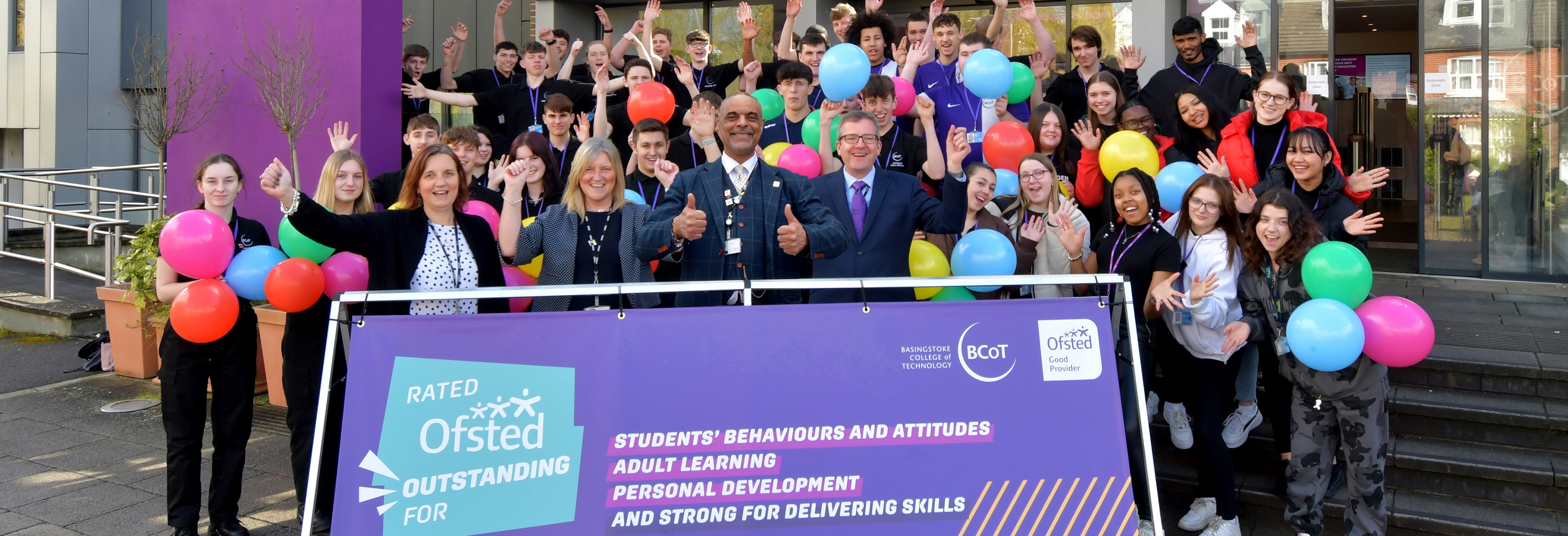 College students and staff smiling at camera with balloons and banners in celebratation