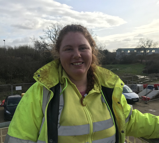Woman in construction gear smiling outside