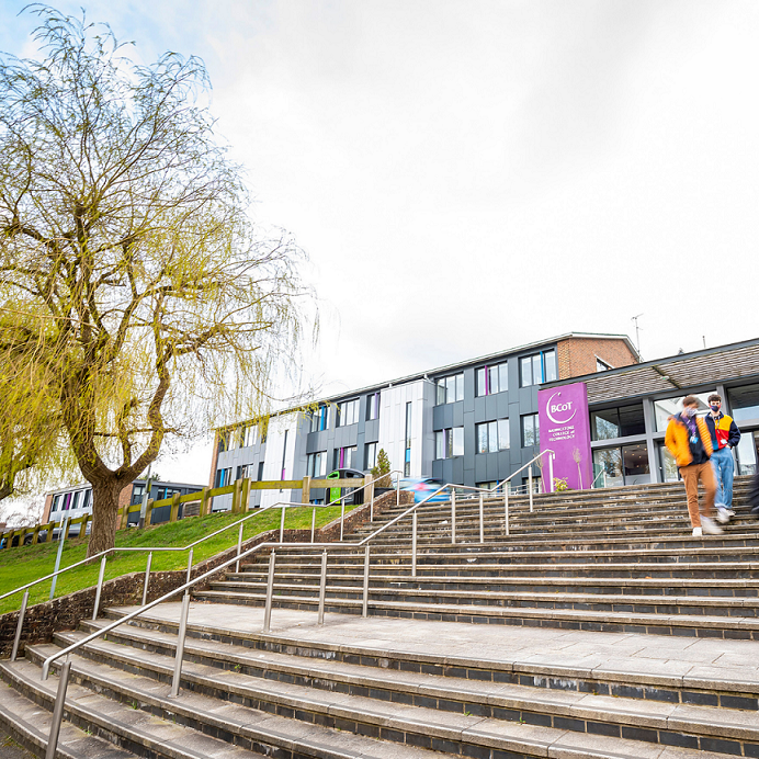 Front of the college with students walking up the stairs